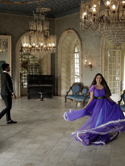 A dynamic "twirling" shot in a grand ballroom. The flowing purple gown creates a beautiful sense of movement, perfect for a fun and elegant pre-wedding photo.