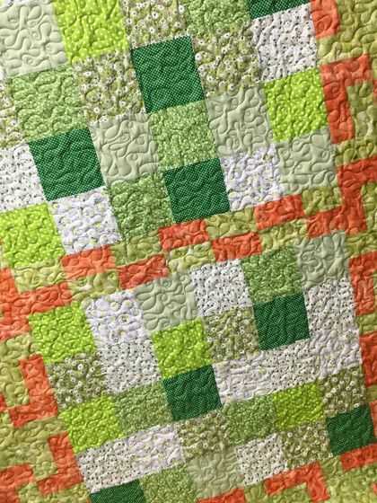 A bright and cheerful patchwork quilt in shades of green and orange.