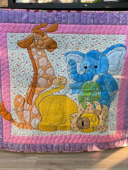 A charming baby quilt with large, friendly appliqué animals, including a giraffe, elephant, and lion.