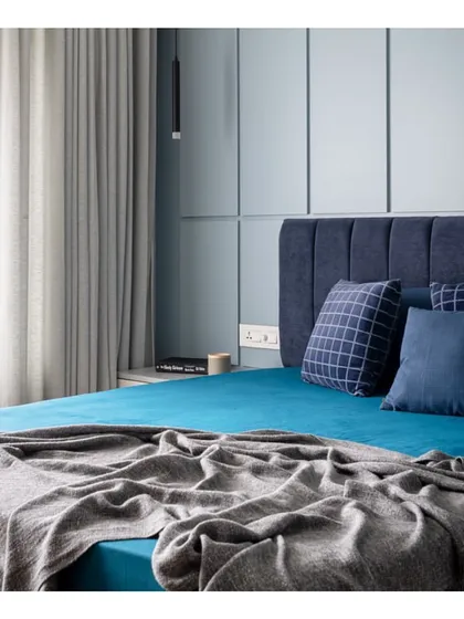 We used a calming palette of blues in this bedroom to create a restful sanctuary. The deep blue headboard and teal bed linens are complemented by the softer blue-grey tones of the paneled wall.