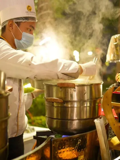 A chef at our live station, tending to large multi-tiered steamers filled with delicious, hot momos, ready to be served.
