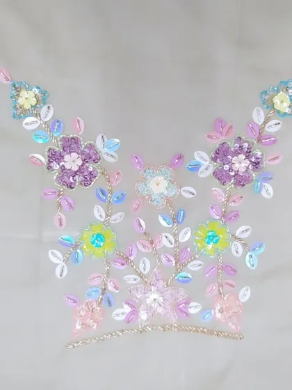 This image shows a neckline motif created with multi-colored sequins and beads. This kind of detailed hand-embroidery allows me to create completely custom patterns that reflect your personal style and the theme of your event.
