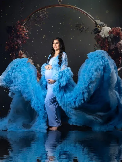 I created this magical, dreamy look right in my studio. The flowing blue gown, the dark floral ring, and the water reflection effect all come together to make the mom-to-be look like a goddess. This shows how we can create fine art maternity portraits.