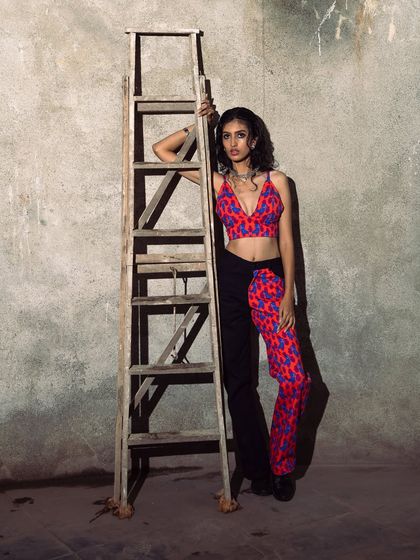 A full-length shot that showcases the unique, two-toned outfit against the raw, concrete background.
