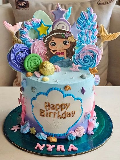 A vibrant mermaid-themed cake with colorful frosting, mermaid tails, and under-the-sea details.