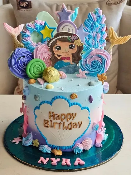 A vibrant mermaid-themed cake with colorful frosting, mermaid tails, and under-the-sea details.