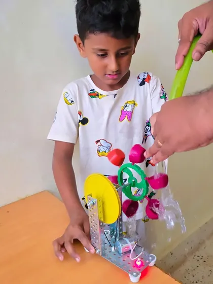 We explore engineering principles with fun, practical experiments. This student is testing a water turbine they assembled, discovering the power of hydro energy by turning a simple flow of water into mechanical motion.