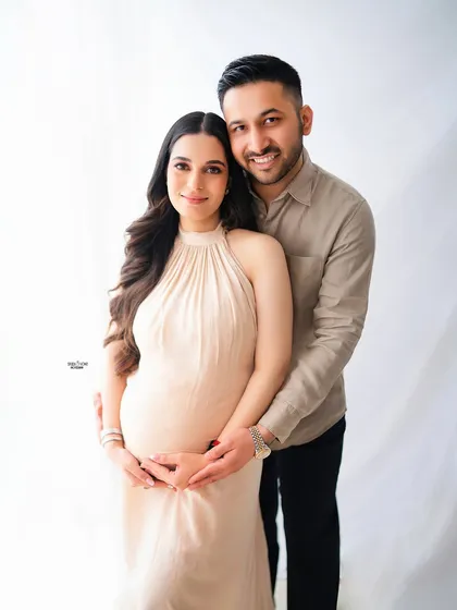 A beautiful, classic portrait of the couple looking at the camera. The partner's hands gently framing the baby bump is such a lovely touch.