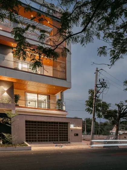 Another evening perspective of the Hennur residence, capturing the light trails and the home's relationship with its surroundings. The lit balconies and soffits add depth and dimension to the contemporary facade.