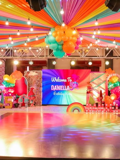 A wide view of the Trolls party stage and dance floor. The rainbow dance floor, colorful ceiling, and bright LED screen create an immersive and high-energy atmosphere.