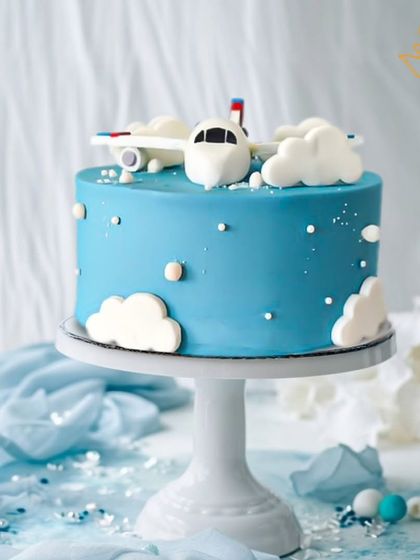 An airplane-themed cake soaring through fluffy clouds. This beautiful blue cake is perfect for a little one with big dreams of flying.