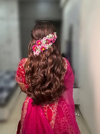 A half-updo with voluminous waves, adorned with a line of fresh pink flowers.