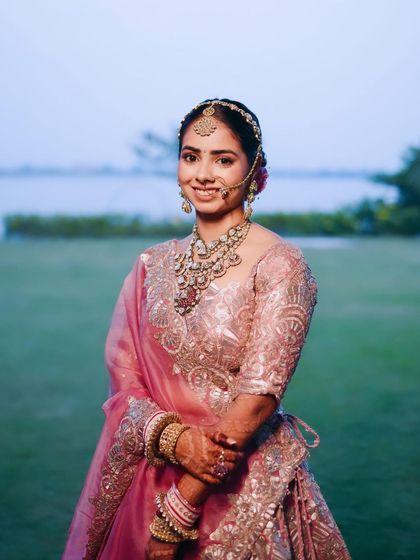 A beautiful portrait by the water. This look for Tanisha features a classic bridal updo and subtle makeup that enhances her features without overpowering them, perfect for a serene outdoor setting.