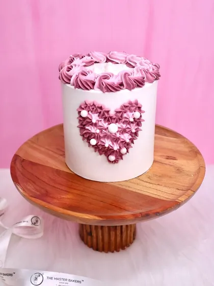 A beautiful heart-shaped cake decorated with piped frosting, perfect for Valentine's Day or an anniversary.