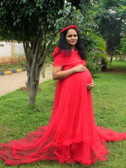 This red butterfly-style maternity gown is a beautiful choice for an outdoor shoot. The sheer fabric and long train create a soft, ethereal look in the natural garden setting.