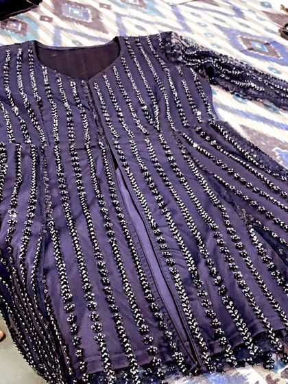 A deep purple suit with vertical lines of sequin work. This jacket-style piece is perfect for creating a layered, contemporary ethnic look.