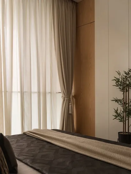 The beauty of simplicity. Sheer and heavy curtains are layered to control light and add softness, while a faux bamboo plant brings a touch of nature indoors.