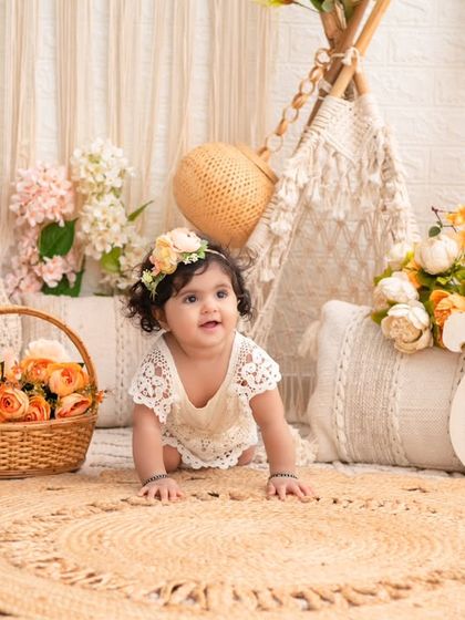 A crawling baby girl in a beautiful peach and cream boho setup. The natural light and earthy tones create a warm and inviting atmosphere.