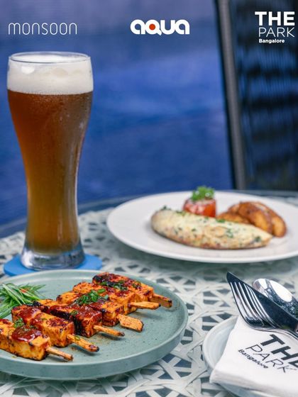 The perfect pairing of spicy paneer tikka and a cold craft beer, enjoyed by the pool at Aqua.