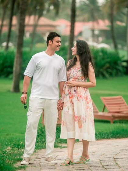 A relaxed walking shot of a couple hand-in-hand through a beautiful garden, capturing a natural and happy interaction.