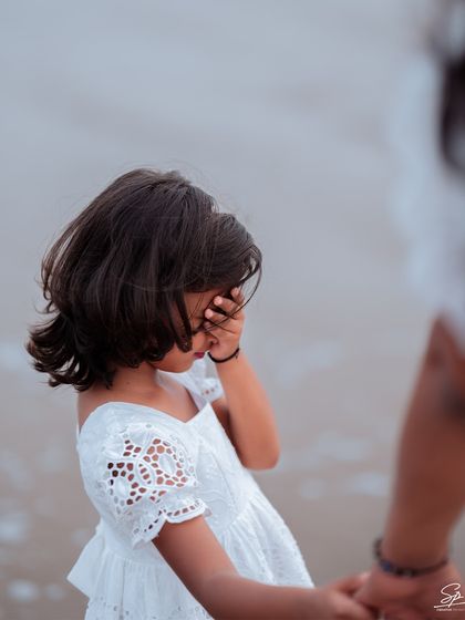 A candid, emotional close-up of the little girl, hand to her face, holding her mother's hand just out of frame. This image captures a fleeting, authentic moment that is full of unspoken feeling, a hallmark of my documentary approach to family photography.