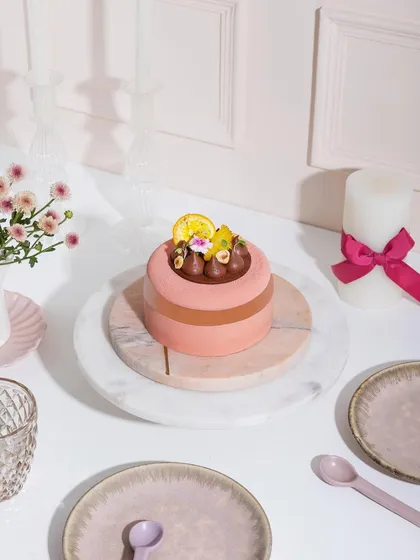 A wider shot of our pink entremet, set on a beautifully arranged table. We are here to make every moment sweeter.