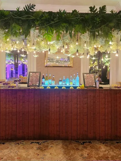 We designed this stunning bar for a cocktail night, with a ceiling of hanging greenery, baby's breath, and Edison bulbs for a chic, rustic-glam vibe.