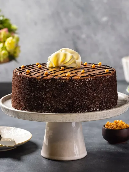 A butterscotch-flavored cake, styled with butterscotch crunchies. The soft, diffused lighting gives the image a gentle and appealing quality.