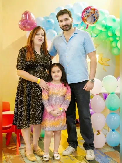 A family of three stands together at their daughter's birthday party. We capture these simple, happy family moments that you'll cherish for years.