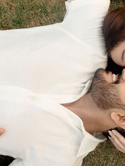 An intimate overhead shot capturing a tender moment between the couple as they lie on the grass.