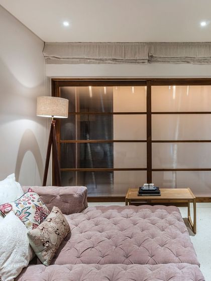 The den in the Terrazzo Residence features a comfortable, tufted daybed in a soft mauve fabric, creating a perfect nook for relaxation and reading.