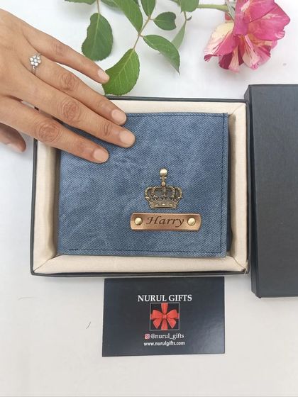 A blue denim wallet personalized for 'Harry' with a crown charm, beautifully presented in its gift box.