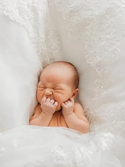 A creative newborn portrait where the baby is nestled in the soft lace of a wedding dress. We can incorporate meaningful family items into your session.