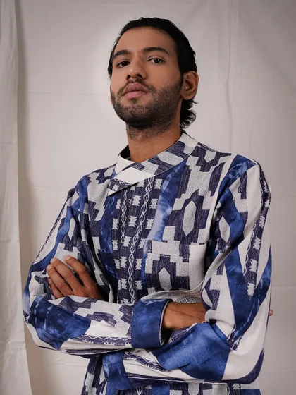 A powerful close-up shot of a model with his arms crossed, wearing a modern printed shirt. This pose exudes confidence and allows a detailed view of the shirt's unique pattern and texture.