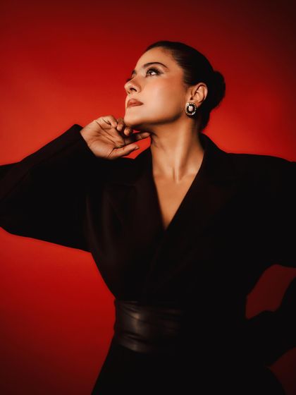 A striking upward-looking pose that highlights the statement earrings and the clean lines of the dress.