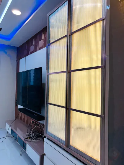 An angled view of the fluted glass mandir, showing how it complements the adjacent TV unit and textured wall.