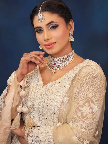A dazzling look in a white embellished outfit. The makeup features a silver and purple cut-crease eye, perfect for a glamorous evening event.