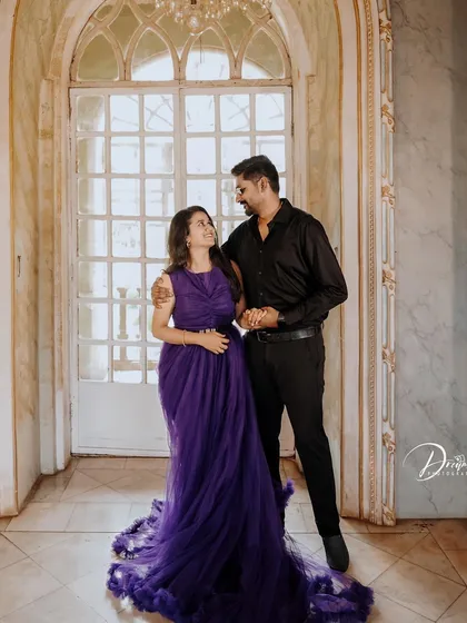 An elegant pre-wedding portrait in a grand hallway. The deep purple gown with its long, ruffled train adds a touch of royalty to the photo.