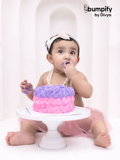 A close up on the cake smash action! This little girl is enjoying her sweet treat, with purple frosting to prove it.