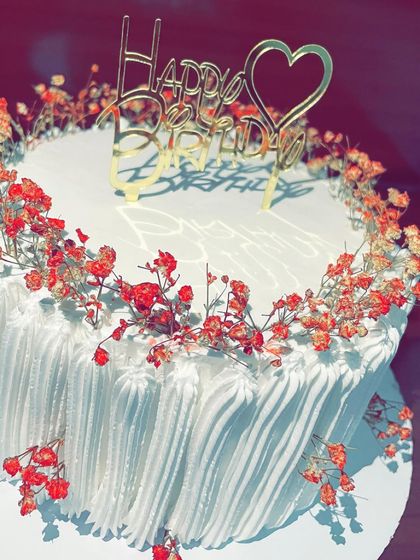 Simplicity can be stunning. This elegant white cake is adorned with a wreath of delicate dried red gypsophila flowers, offering a minimalist and beautiful option for a birthday or anniversary.