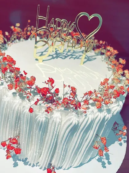 Simplicity can be stunning. This elegant white cake is adorned with a wreath of delicate dried red gypsophila flowers, offering a minimalist and beautiful option for a birthday or anniversary.