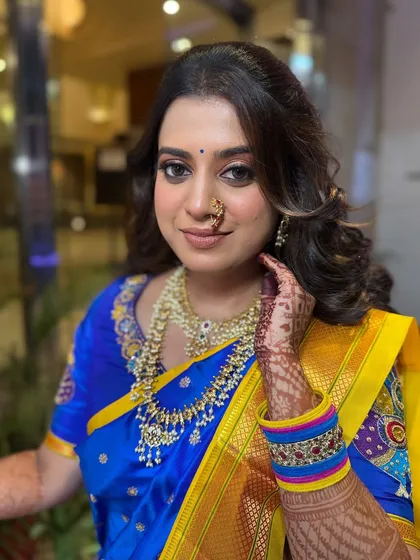 A beautiful close-up of this bride's engagement look, featuring a royal blue and yellow Paithani saree. The makeup is kept fresh and radiant to let the vibrant colors of her outfit shine.