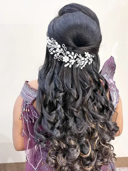 Voluminous curls for a reception look, held in place with a sparkling hair accessory. This style adds glamour and movement.