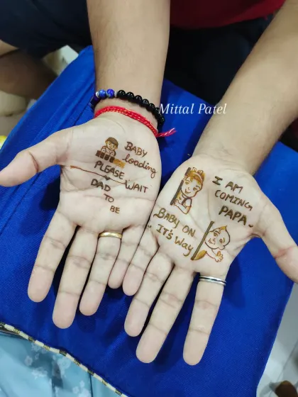 A fun and unique mehndi design for the dad to be. The palms feature cute messages like "Baby loading, please wait" and "I am coming Papa" alongside adorable doodles of a baby and parents.