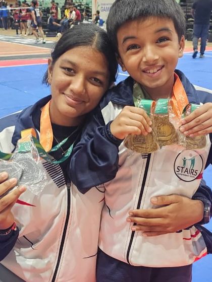 Two of our young athletes proudly displaying their medals from the Stairs National Games. Their smiles represent the joy of achieving their goals.