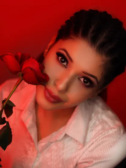 A dramatic portrait with a red rose and intense red lighting. This creative shot is great for artistic projects, fragrance campaigns, or Valentine's Day themed promotions.