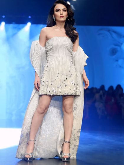 A full-body shot of Radhika Madan, highlighting the unique structure and embellishments of her white outfit.