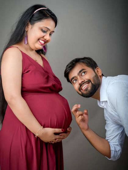 A playful moment filled with anticipation and joy. The dad-to-be's excited expression as he listens to the baby bump makes this a fun and heartwarming couple's portrait.