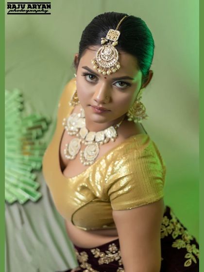 This high-angle portrait creates a captivating and intense look, drawing attention to the model's expression and the detailed 'maang tikka'. The lighting is carefully controlled to sculpt her features.