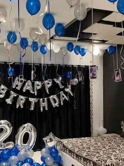 A cool blue and silver theme for a 20th birthday room decoration. The setup includes balloons on the ceiling with hanging photos, foil letters, and number balloons.